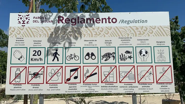 A park regulations sign displays allowed and prohibited activities with bilingual text and icons, including speed limits, walking, cycling, wildlife viewing, an A park regulations sign displays allowed and prohibited activities with bilingual text and icons, including speed limits, walking, cycling, wildlife viewing, an