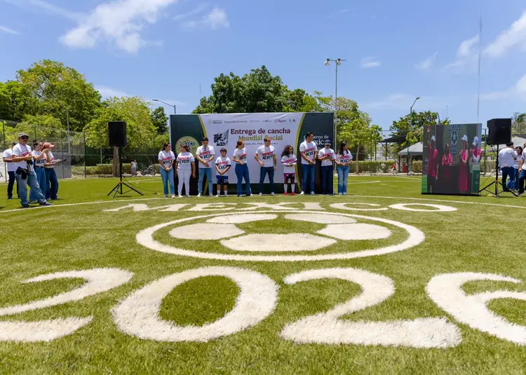 Group of people wearing matching shirts stand on a soccer field with large white numbers and smiley face painted on the grass during an outdoor event Group of people wearing matching shirts stand on a soccer field with large white numbers and smiley face painted on the grass during an outdoor event
