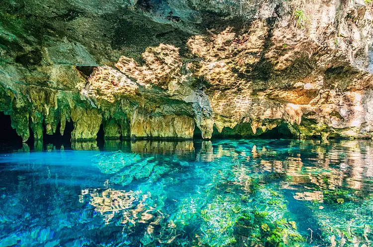 Underground cave with turquoise water and moss-covered limestone walls and formations Underground cave with turquoise water and moss-covered limestone walls and formations