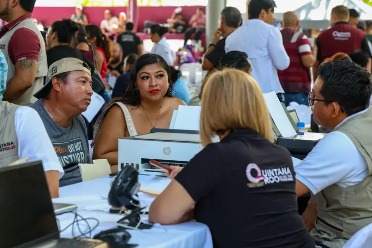 People sit at tables with laptops during a crowded indoor event offering financial services and information People sit at tables with laptops during a crowded indoor event offering financial services and information
