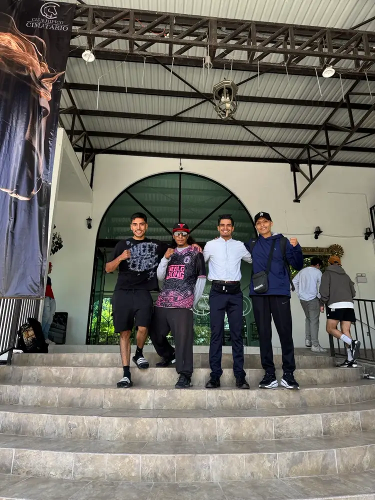 Four men pose on steps outside a building with a large green arched doorway, with other people visible in the background Four men pose on steps outside a building with a large green arched doorway, with other people visible in the background