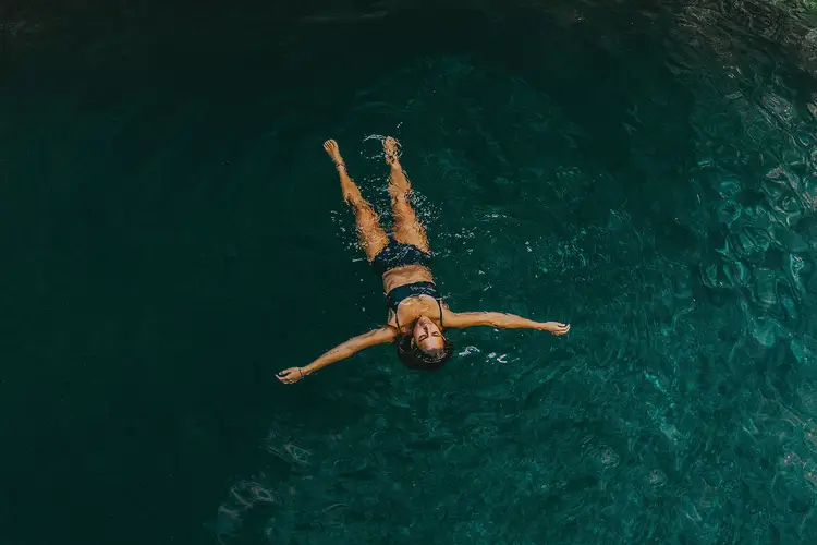 Person floating on their back in clear turquoise water, viewed from above Person floating on their back in clear turquoise water, viewed from above