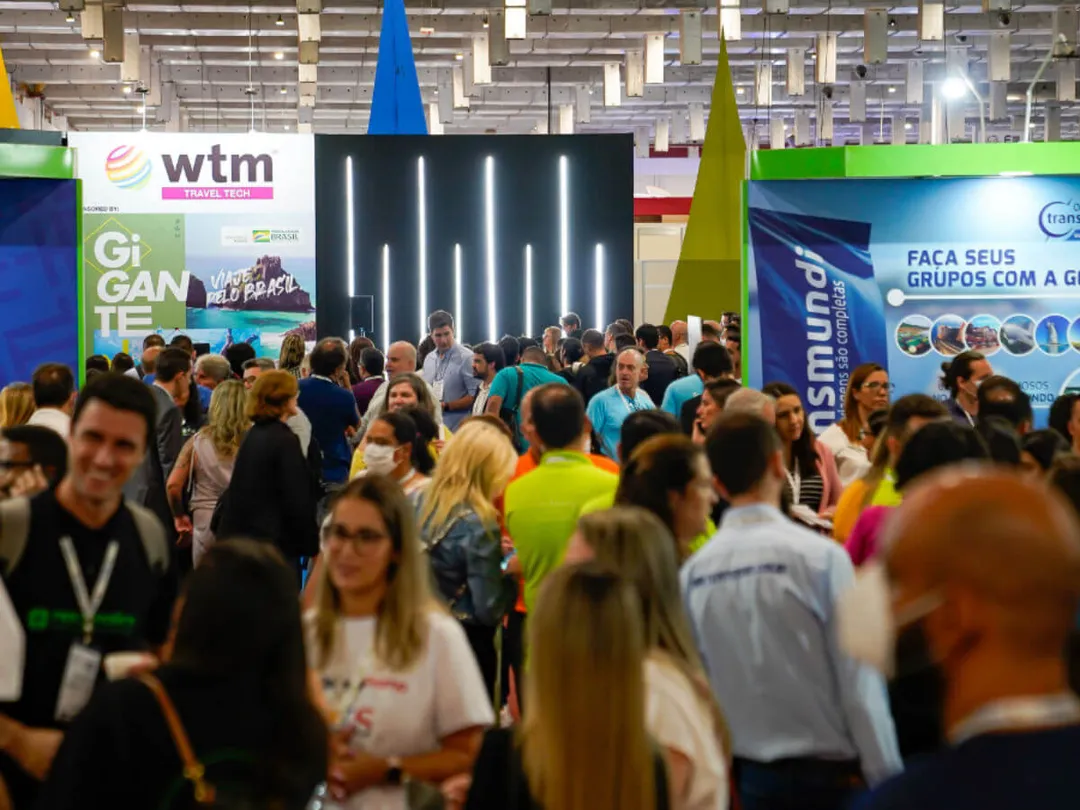 Tulum Strengthens Global Presence at WTM Latin America in Brazil A large crowd of people gathers around illuminated display booths at an indoor trade show or conference hall