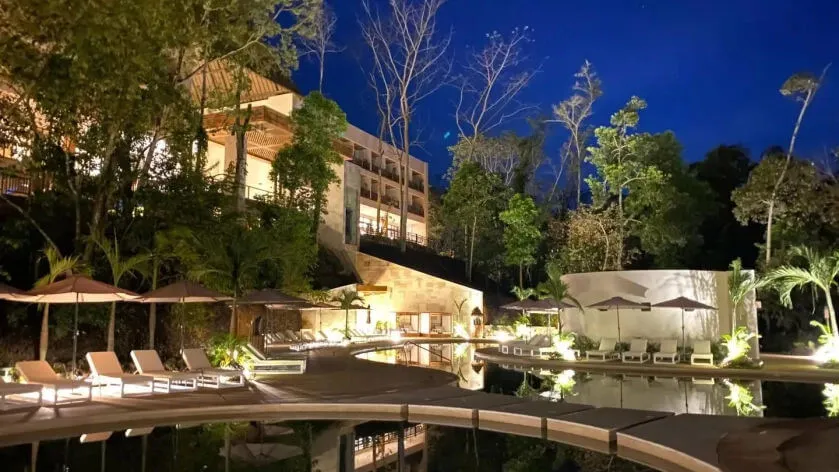 Maya Train Boosts Hotel Occupancy to 50% by 2025 Resort pool deck at dusk with loungers, umbrellas, and a multi-story hotel building surrounded by tropical vegetation
