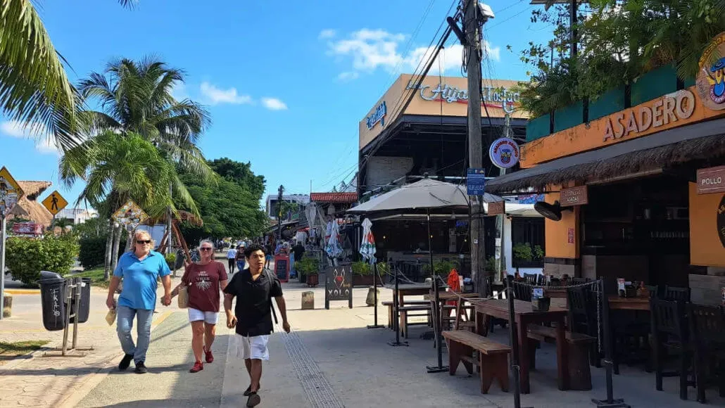 Tourism Decline Alarms Mexico’s Caribbean Sector Pedestrians walk past shuttered storefronts and restaurants with boarded windows along a beachside commercial street