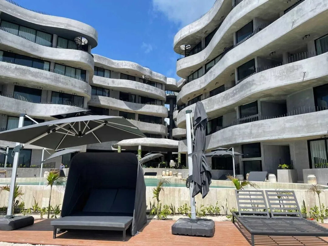 Illegal Construction in Soliman Bay Curved concrete apartment buildings with balconies overlook a poolside patio area with lounge chairs and umbrellas