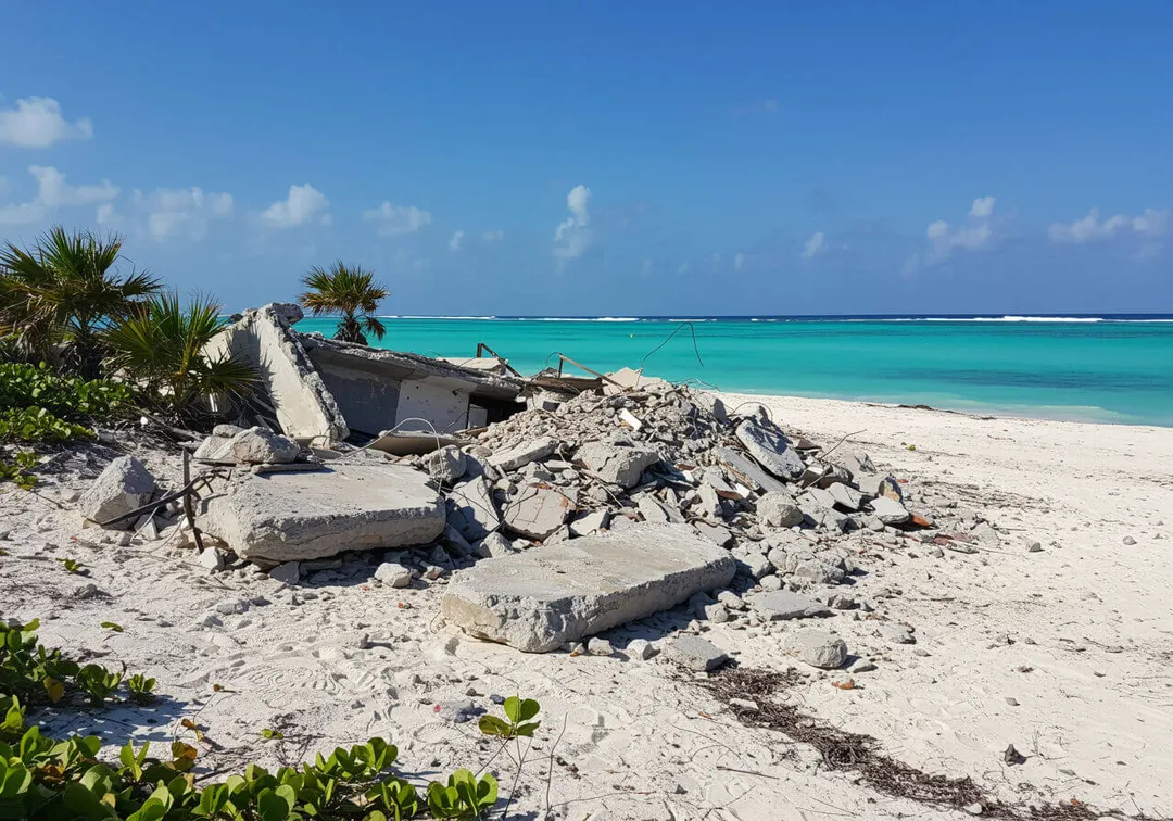 Tulum’s corruption fuels environmentally harmful developments Concrete rubble and debris scattered across a sandy beach with turquoise water and palm trees in the background
