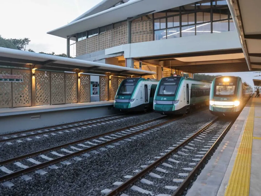 MayaPass Unlimited Train Pass: 30-Day Merida to Tulum Access Multiple passenger trains stopped at a modern station platform with a contemporary building and latticed shade structures