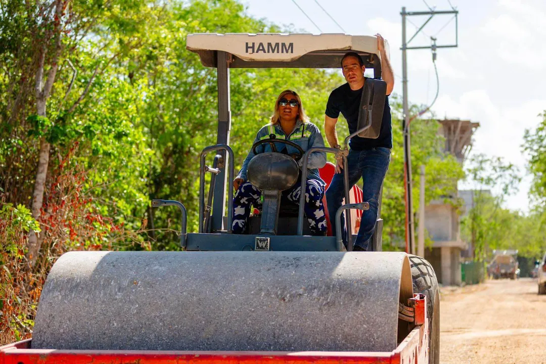 Tulum Region 15 Road Paving Accelerates with Major Upgrades Two people operate a road roller on a dirt street lined with green vegetation and utility poles