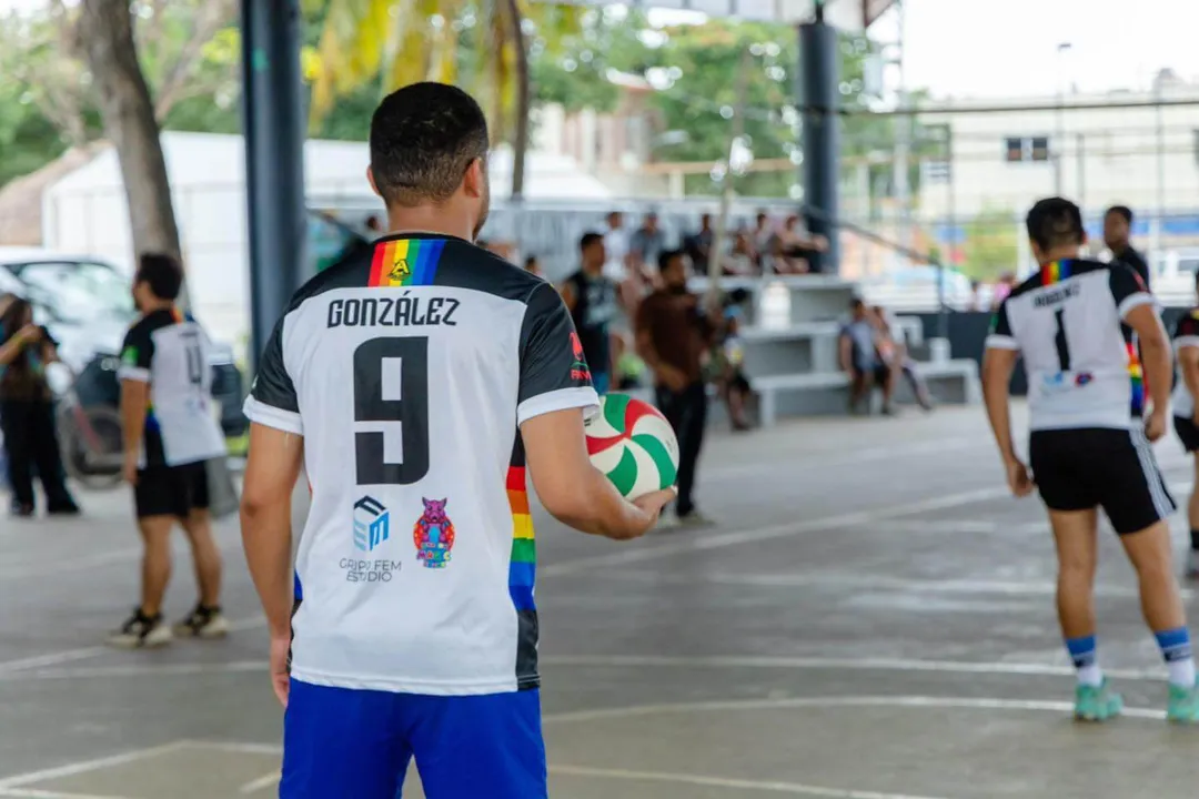 Community Building in Tulum Through Inclusive Sports Competitions Volleyball player wearing number 9 jersey holds ball during outdoor sports competition with spectators and other players in background