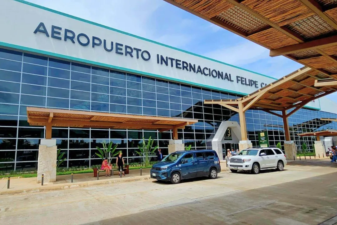 Airlines respond to Tulum International Airport incentives push Two vehicles parked outside an airport terminal building with large windows and wooden architectural elements