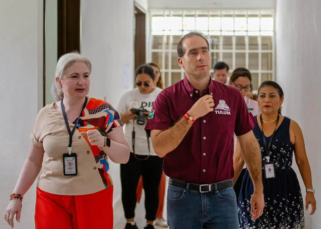 Tulum invests in sensory therapy for autism with a new inclusive care center A man in a maroon polo shirt and a woman in a beige top walk together down a hallway with several other people following behind them, all wearing visitor badges