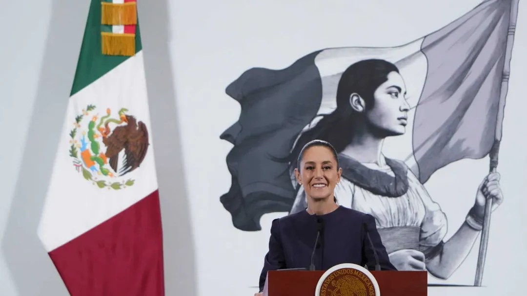 Mexico deploys National Guard to ensure safety in top beach destinations Woman speaking at a podium in front of the Mexican flag and a mural depicting a figure holding a flag