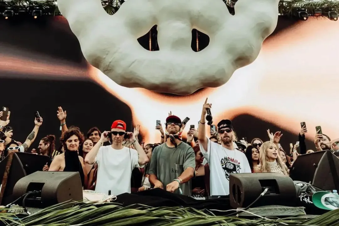 Keinemusik returns to headline Zamna Tulum Festival 2026 DJs perform at a festival stage while a large crowd behind them raises their hands and phones in the air