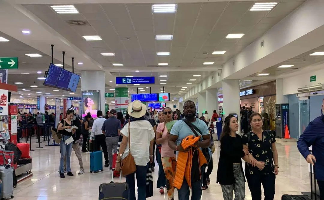 Why Canadian tourists in Mexico are choosing Quintana Roo over the United States Travelers with luggage stand in a busy airport terminal with directional signs and departure boards overhead