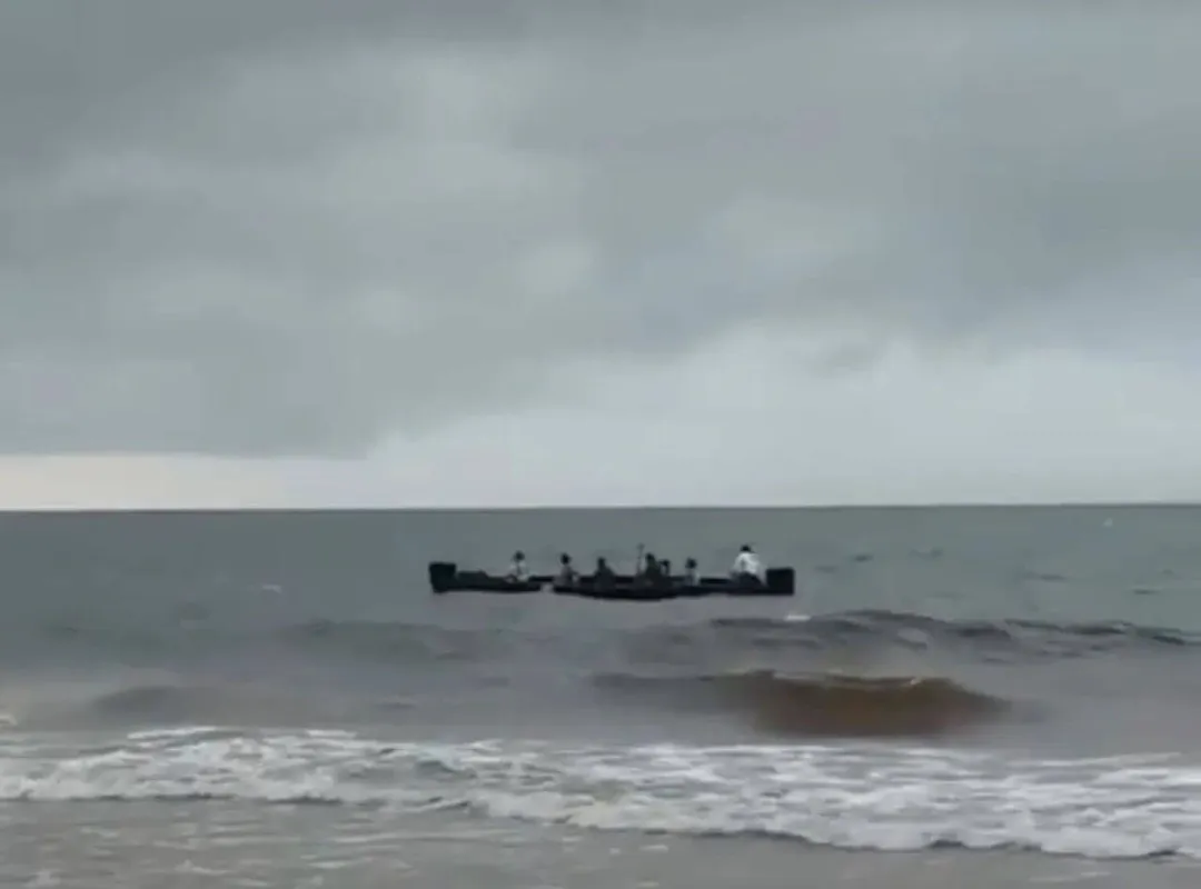 Viral video in Tulum sparks confusion over Cuban migrants arrival A dark vessel sits in shallow ocean water near the shore as waves roll toward the beach under overcast skies