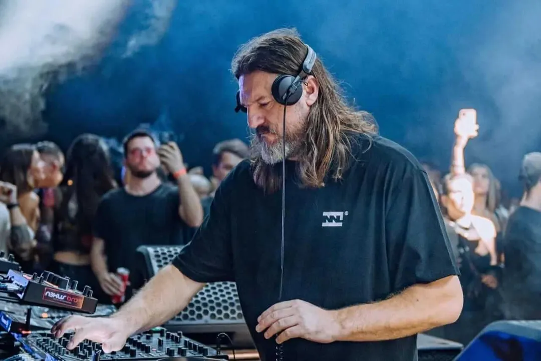 Solomun headlines Tulum music festival at Tehmplo in January 2026 DJ wearing headphones operates turntables while performing in front of a crowd at an indoor music venue with blue lighting
