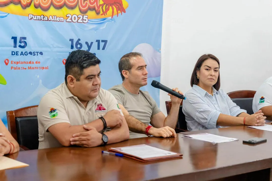 This Lobster Festival in Tulum Is a Hidden Recipe for Local Revival Three people sit at a table during a press conference with a festival banner visible behind them