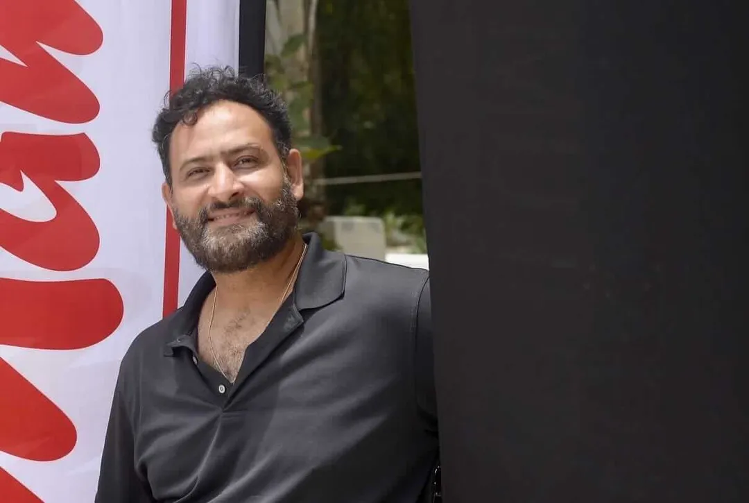 How a Small Archery Club in Tulum Is Building Big Dreams A bearded man in a black shirt stands next to a red and white banner outdoors