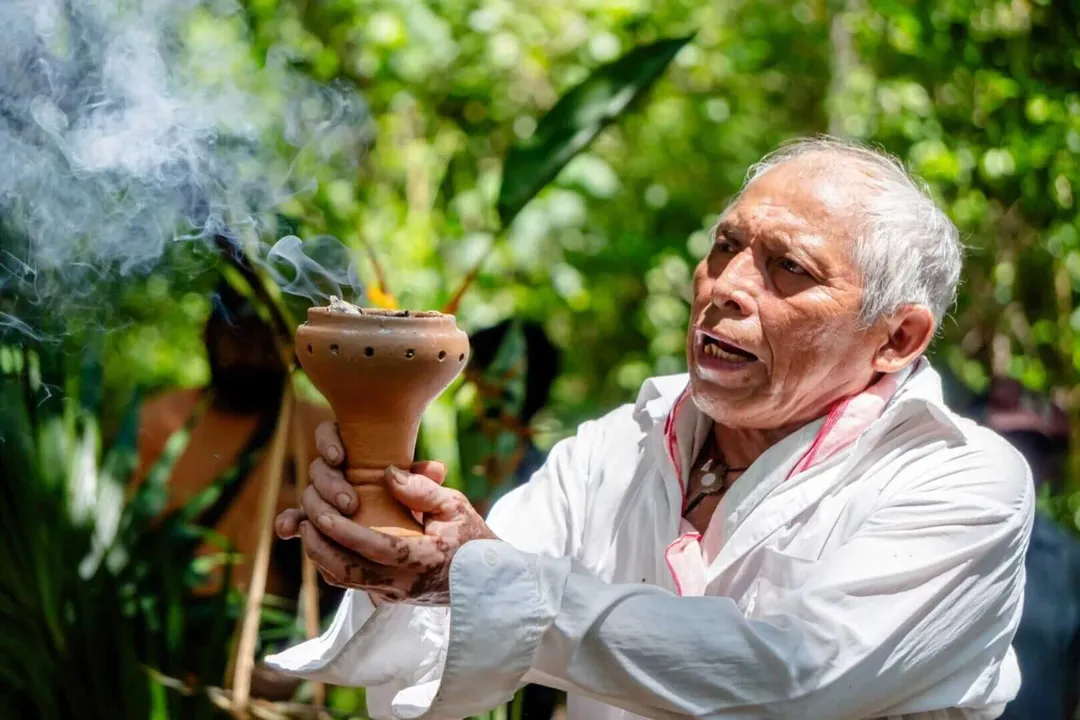 Cobá’s National Bee Day Turned the Town into a Living Hive Man holding a smoking clay vessel outdoors surrounded by green foliage