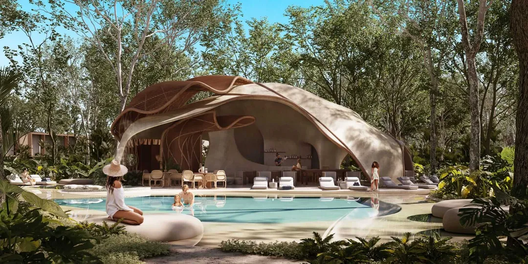 Turn the Spirit of Tulum into Your Home with Ramia A woman sits poolside near a curved, organic-shaped structure with an open interior overlooking a swimming pool surrounded by trees
