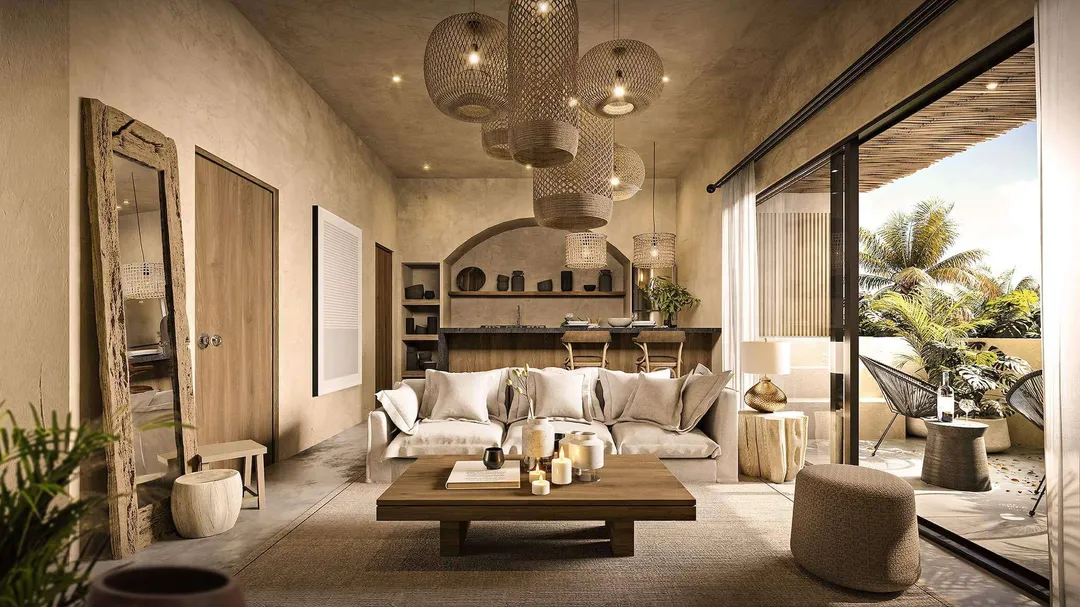 Who’s Winning in Tulum’s Evolving Property Market? Modern living room with beige sofa, wooden coffee table, and pendant lighting, opening to a palm-lined terrace through glass doors