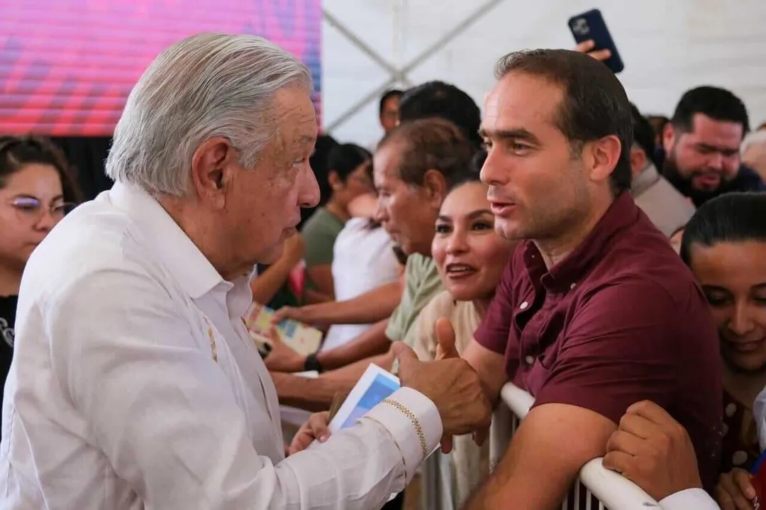 Tulum government blames Tren Maya and airport for local budget crisis Man in white shirt shakes hands with attendees at an indoor public event under a tent
