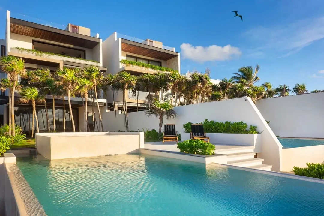 A taste of Mexico’s soul with Chef Please’s new private dining experience Modern beachfront residential complex with swimming pool, palm trees, and multi-level white buildings under clear sky