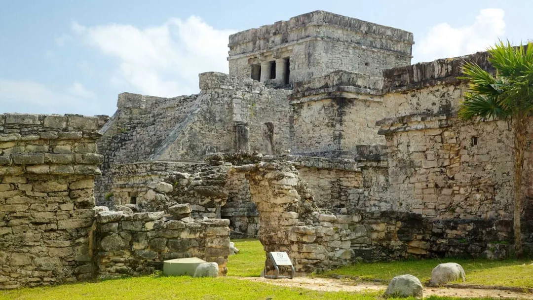 Foreign tourists could pay double to enter Tulum ruins under new law Ancient stone ruins with a multi-level structure stand behind crumbling walls and grass-covered ground