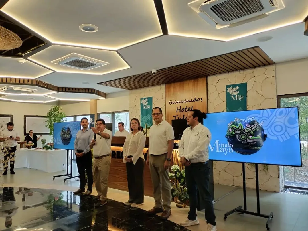 Grupo Mundo Maya’s expansion intensifies tensions in Tulum A group of people stand in a hotel lobby next to a large display screen showing a logo, with reception desk and modern ceiling fixtures visible in the backgroun