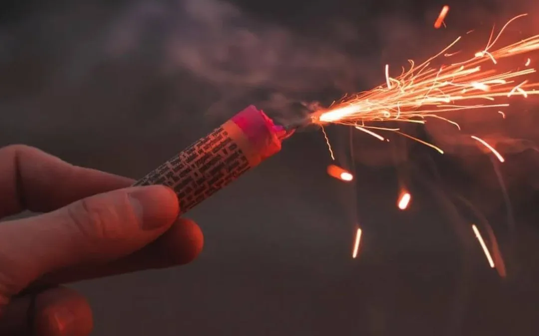 Fireworks safety warnings intensify in Tulum ahead of December festivities A person holds a lit firecracker that sprays sparks into the air against a dark background