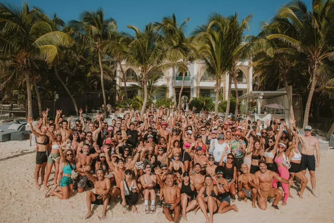 South Tulum’s new IKTAN development phase begins with a 5KM run through raw land Large group of people in beach attire gathered on sand in front of a white building surrounded by palm trees