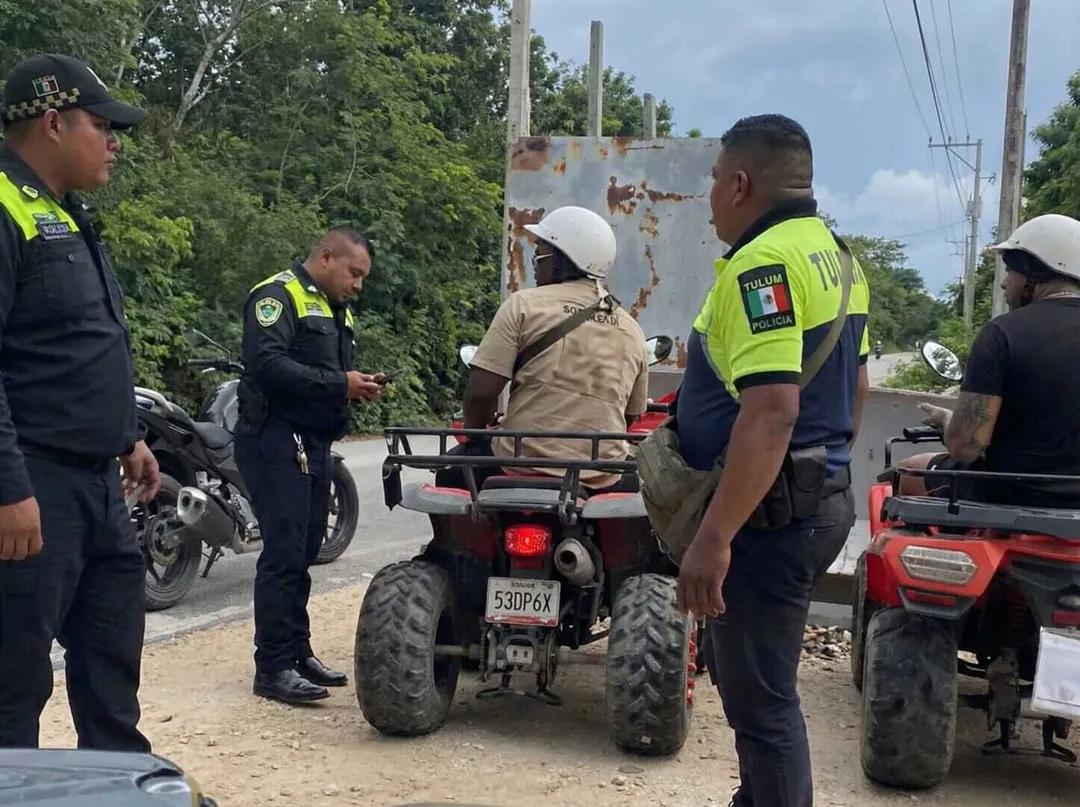 What tourists should know as traffic stop complaints surface in Tulum Police officers in reflective vests conduct a stop near a parked three-wheeler on a rural road lined with trees