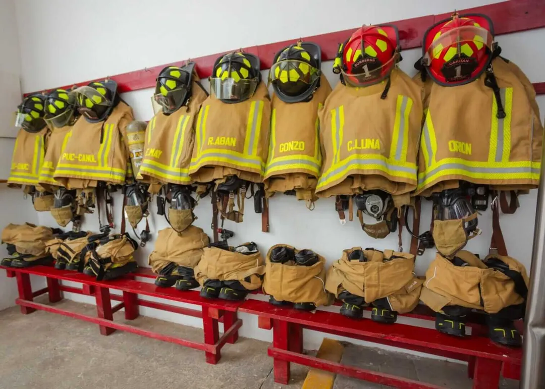 New gear strengthens firefighter safety and response capacity in Tulum Firefighter turnout gear and helmets hang on a red rack with protective equipment stored below