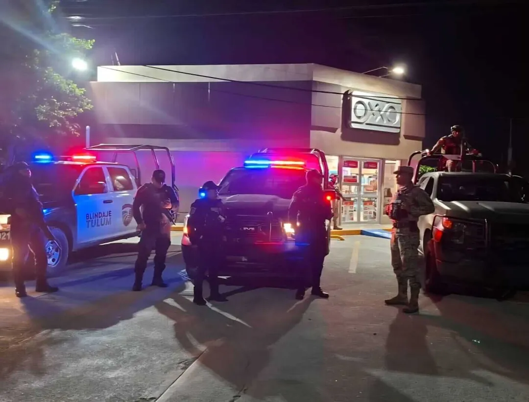 Foreign citizen alleges armed robbery by police in Tulum Police and emergency vehicles with flashing lights surround a commercial building at night while officers stand in the parking lot