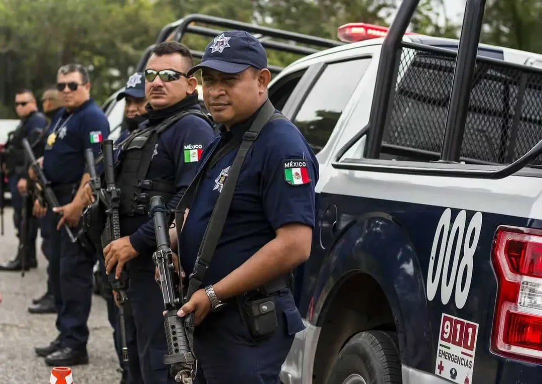 Police officers in dark uniforms stand beside an emergency response vehicle during an outdoor operation