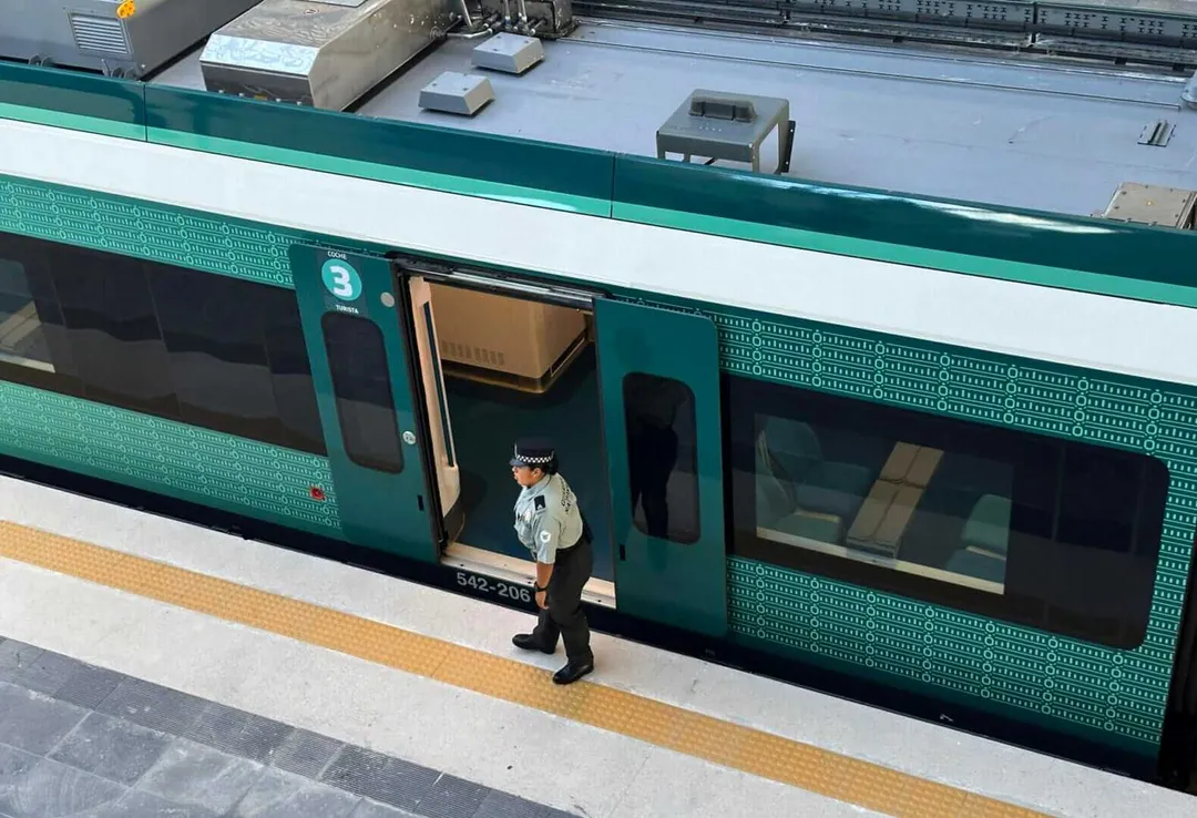 Court orders definitive suspension on Cancun to Tulum Maya Train works Transit worker stands beside a green and white train at a station platform
