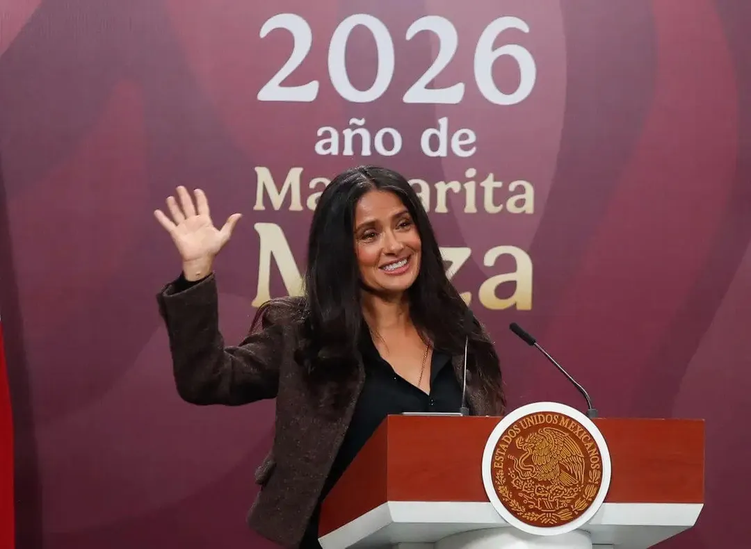 Salma Hayek links Tulum filming to Mexico’s new federal film law Woman with long dark hair wearing a dark blazer waves from behind a podium with an official seal, standing in front of a pink backdrop with Spanish text
