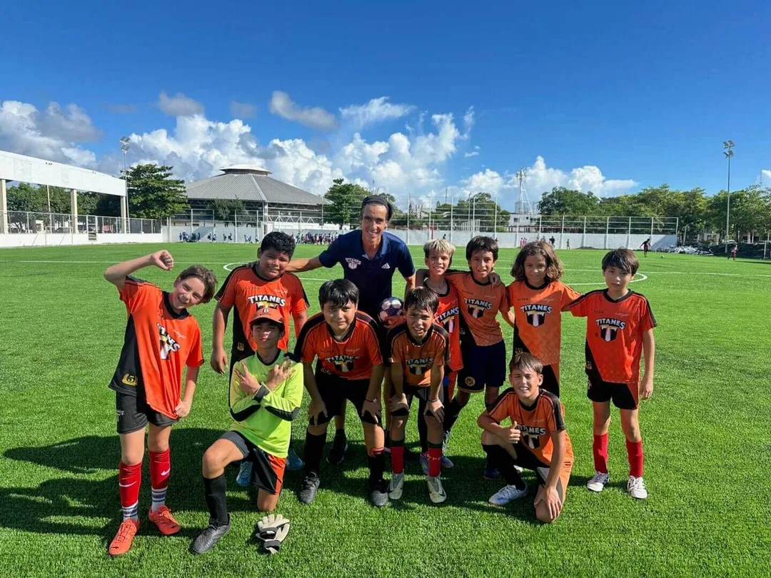 Club Titanes celebrates nine years training youth soccer in Tulum Youth soccer team and coach posing together on a grass field with stadium facilities visible in the background