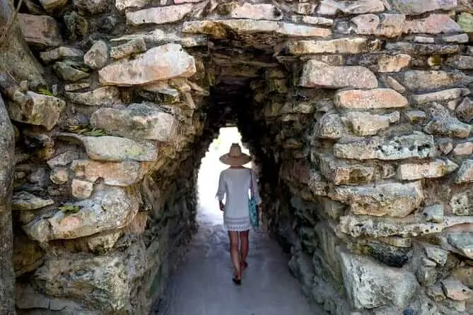Tulum Archaeological Site Surges to Holy Week’s Third Most Visited Person walking through a narrow stone passageway in an ancient ruins structure