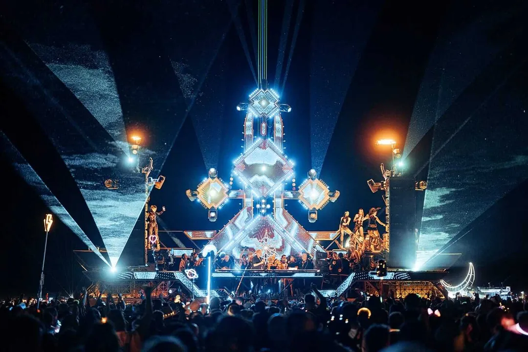 Everything You Need to Know About Zamna Tulum 2026 in Riviera Maya Large illuminated stage structure with geometric diamond-shaped design surrounded by crowds at an outdoor nighttime event in a desert setting