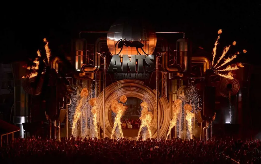 ANTS returns with a world tour linking Tulum’s jungle to London’s steel Large stage with ant logo and silhouette surrounded by pyrotechnics and flame effects during nighttime performance in front of crowd