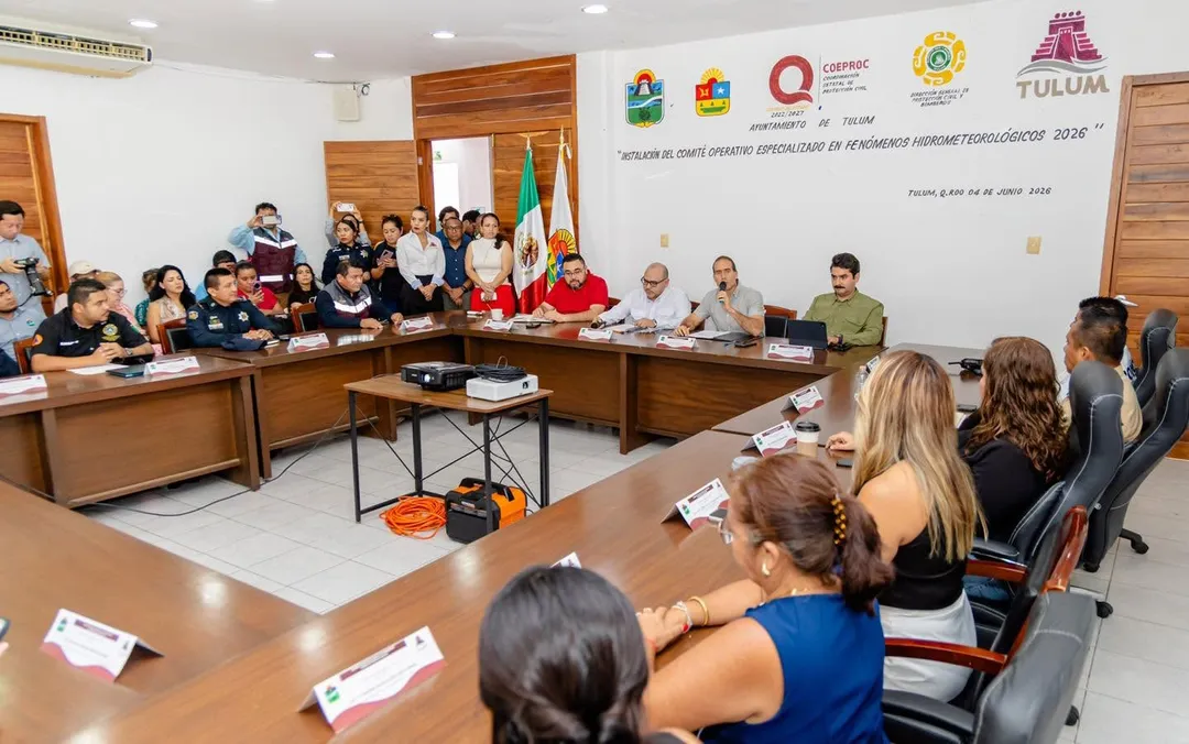 Tulum Activates Emergency Committee and Opens 38 Shelters for the 2026 Hurricane Season Officials and representatives sit around a large conference table during a meeting in a municipal building with Mexican and institutional flags on the wall