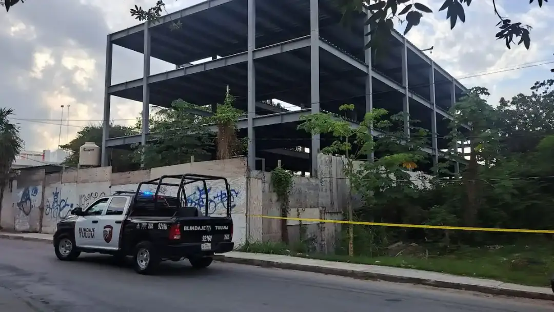 Police vehicle parked outside an abandoned concrete building with yellow caution tape across the front