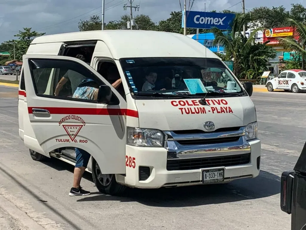 White passenger van with open side door parked in a commercial area with signage visible in background