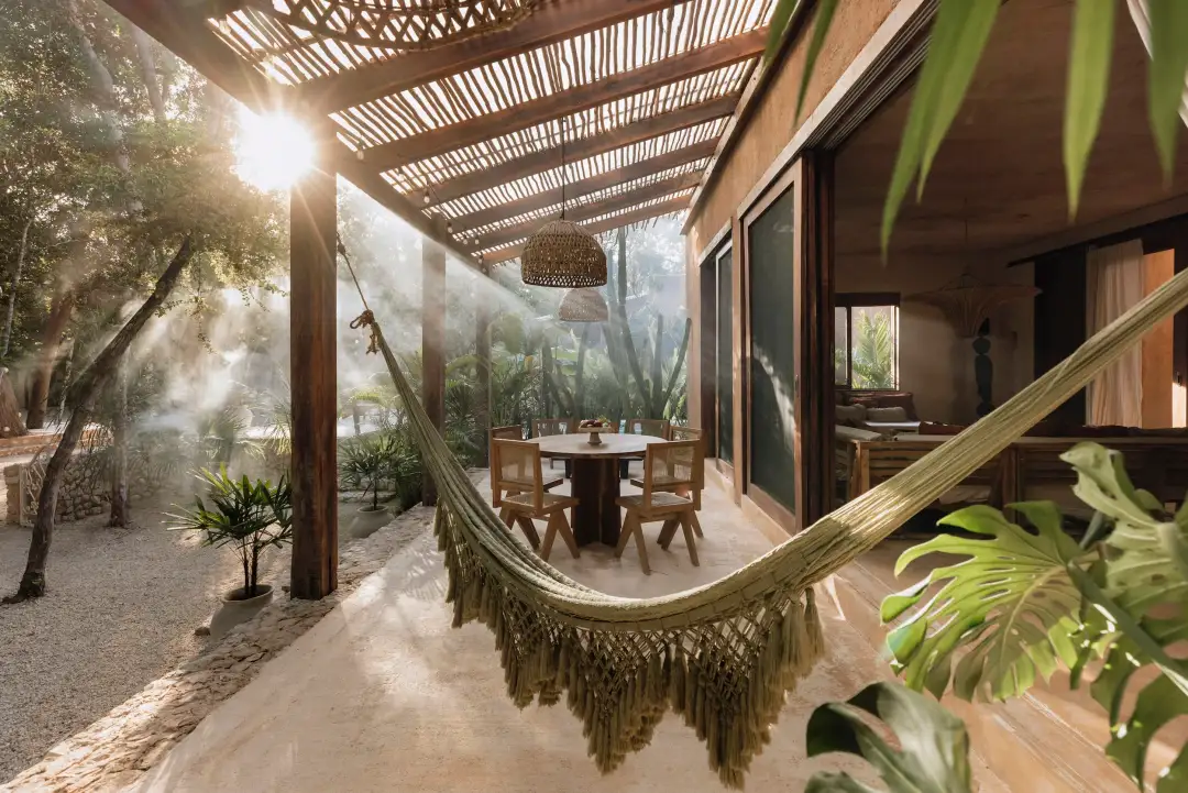 Souljourn Yoga books its first Mexico retreat in Tulum for 2027 A hammock hangs on a covered patio beside a dining table, with tropical plants and palm trees visible in the background under dappled sunlight