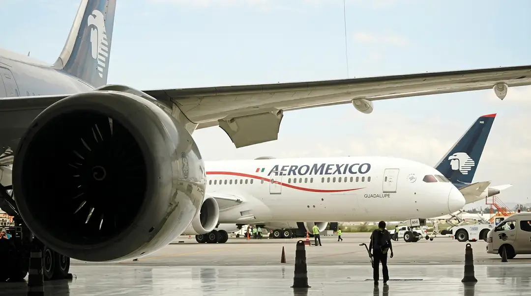 Commercial aircraft parked at an airport tarmac with ground service vehicles and personnel nearby