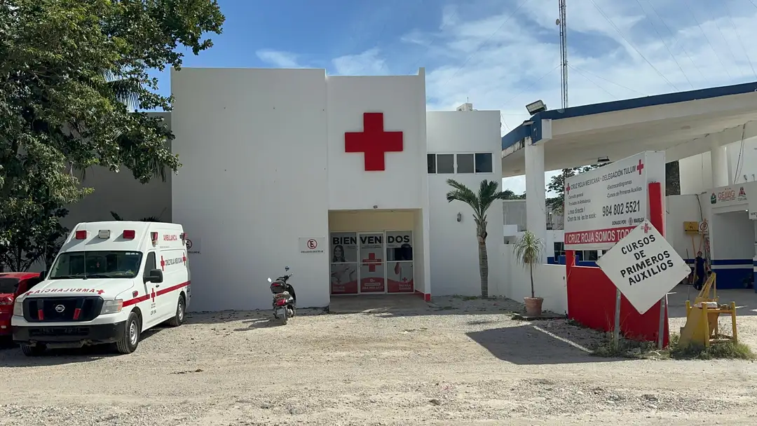 Free HIV and hepatitis C testing opens in August at the Tulum Red Cross An ambulance parks outside a white medical clinic building with a red cross symbol, palm trees and a communications tower visible nearby