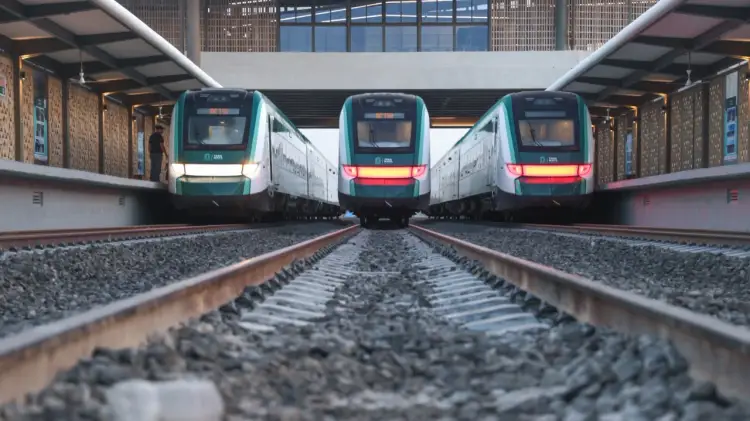 Three modern commuter trains with teal and white livery sit on parallel tracks in an underground station with brick walls and skylights above Three modern commuter trains with teal and white livery sit on parallel tracks in an underground station with brick walls and skylights above