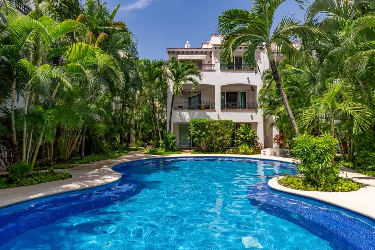 White residential building with pool surrounded by tall palm trees and tropical vegetation